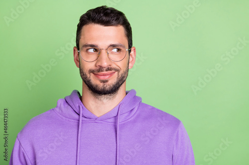 Photo of cute millennial brunet guy look empty space wear eyewear violet hoodie isolated on green color background