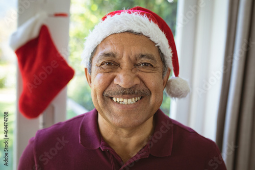 Portrait of happy biracial senior man in santa hat at christmas