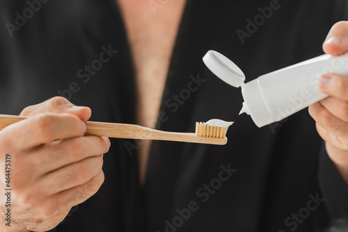 Cropped view of blurred man pouring toothpaste on toothbrush