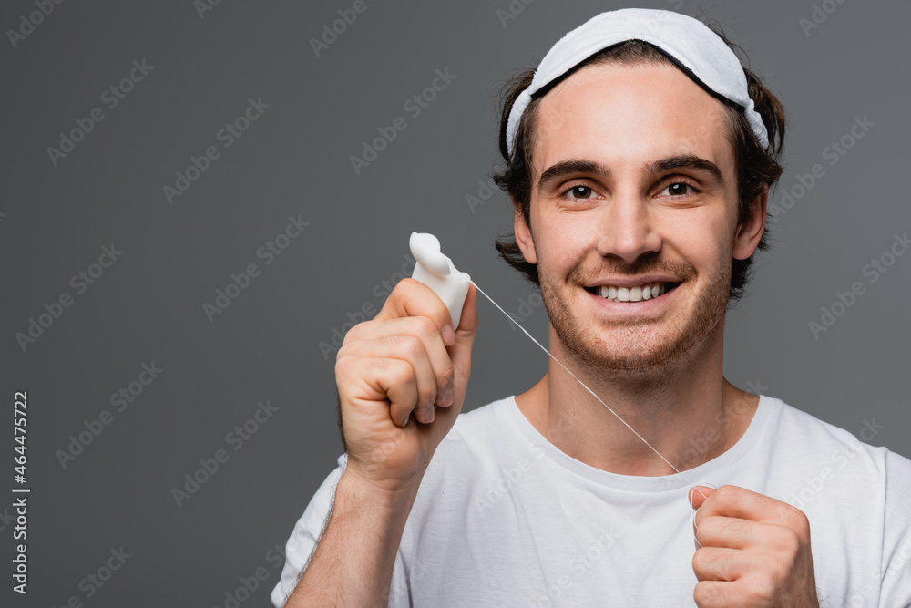 Smiling man in sleep mask holding dental floss isolated on grey Smiling man in sleep mask holding dental floss isolated on grey