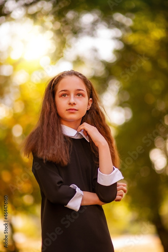 School concept. Little girl 11 years old in a dress on the background of nature in autumn.