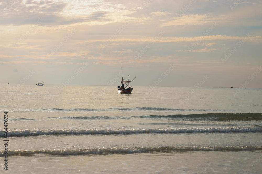The fishing boat floats in the middle of the sea in the evening.