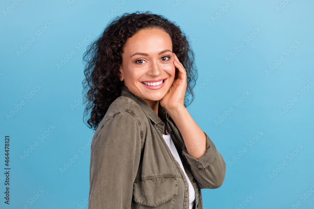 Profile side view portrait of attractive cheerful wavy-haired girl touching face isolated over bright blue color background Profile side view portrait of attractive cheerful wavy-haired girl touching face isolated over bright blue color background