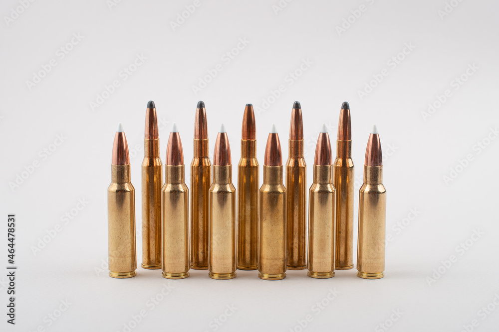 Rifle bullets in a row isolated on grey background. Rifle bullets in a row isolated on grey background.