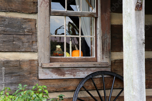 A log cabin window is decorated for the fall season with pumpkins.