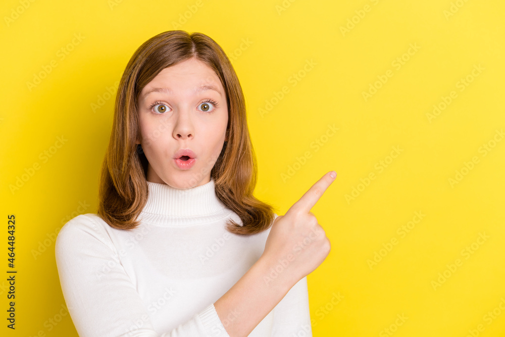 Photo of young girl amazed shocked surprised point finger empty space advert isolated over yellow color background Photo of young girl amazed shocked surprised point finger empty space advert isolated over yellow color background