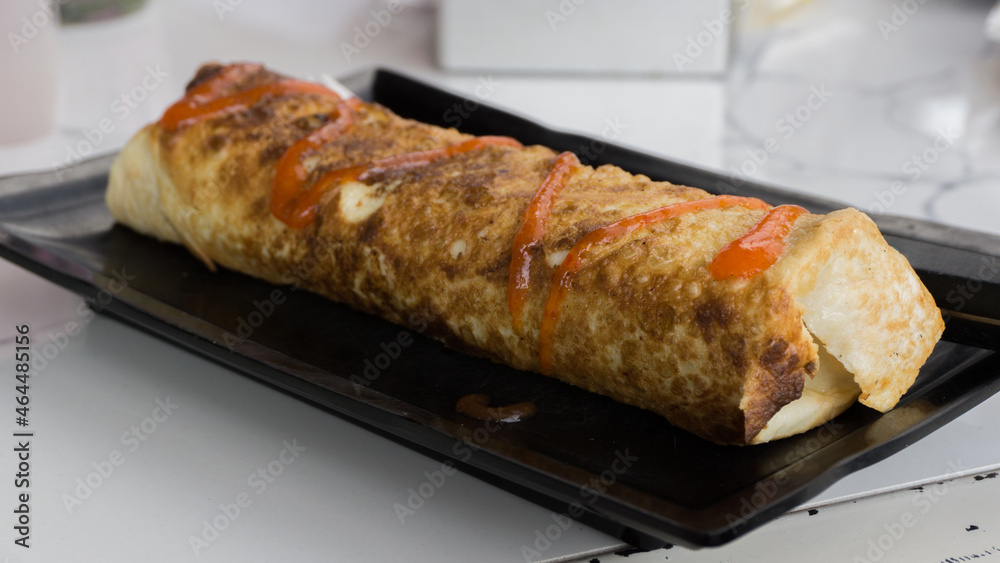 Burrito wraps with egg omelet and vegetables on plate. Turkish kebab with egg omelet and vegetables