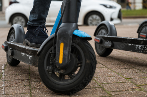 Close-up of a foot on an electric scooter parked on the sidewalk in the city. Ready to use. Urban transport