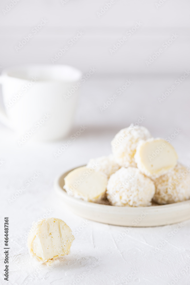 Vegan sweets in coconut flakes on a light background. Sugar, gluten and lactose free.