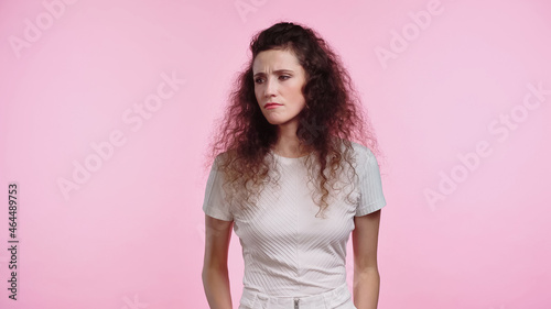 displeased young woman looking away isolated on pink