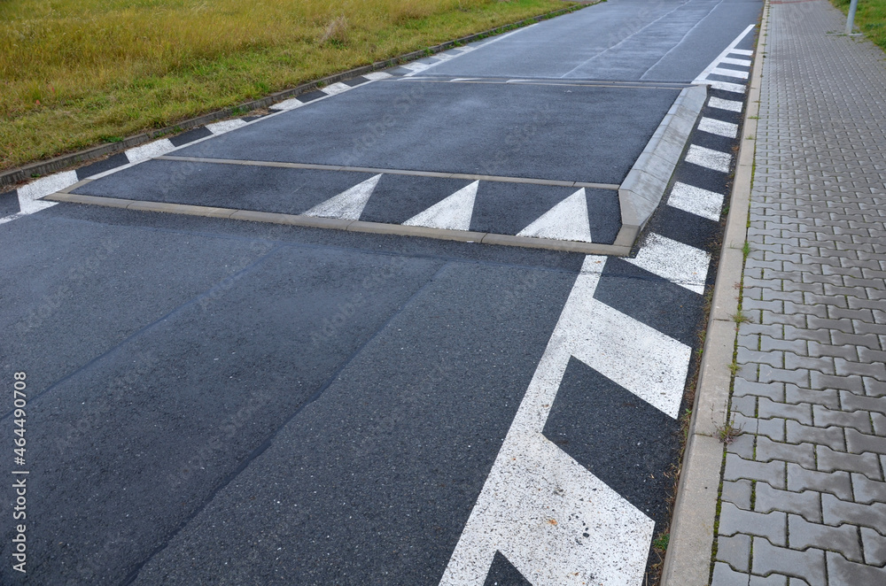 Fototapeta premium a regular square raised above the level of the asphalt road beveled on all sides. overcoming an obstacle means slowing down the vehicle and thus increasing safety in the residential area near school