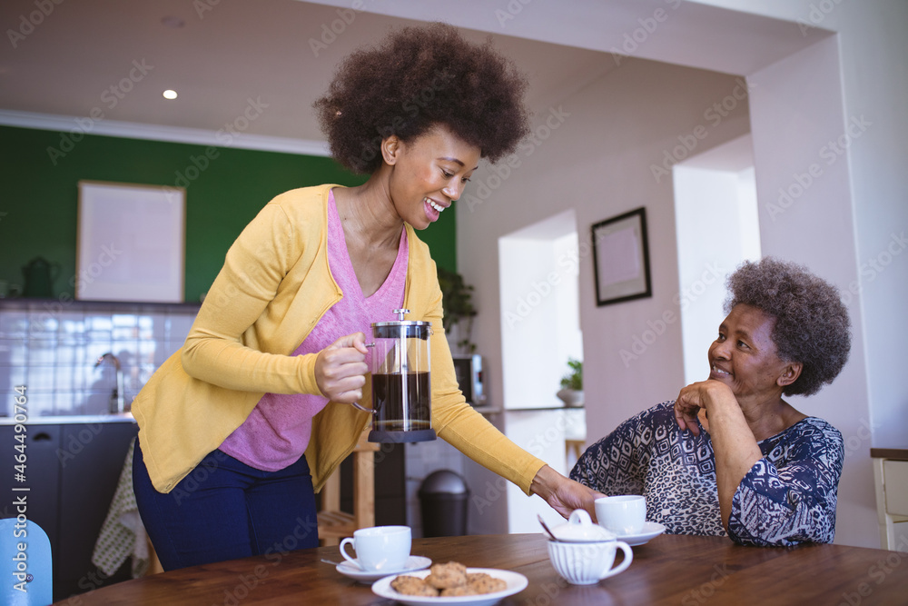 © Wavebreak Media - Smiling african american senior woman with adult daughter drinking coffee in kitchen