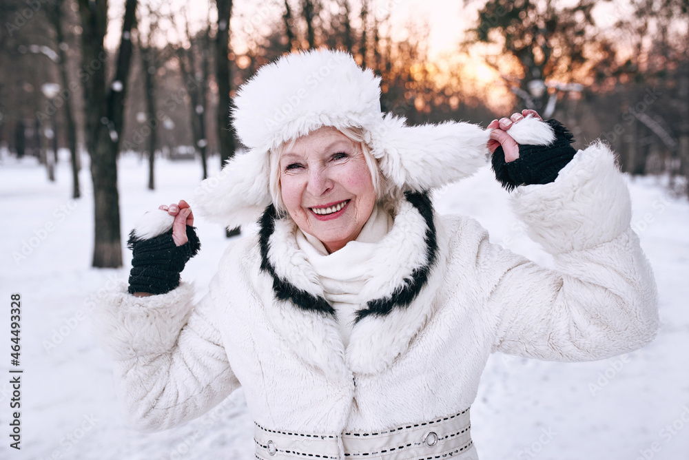 senior woman in white hat and fur coat enjoying winter in snow forest. Winter, age, season concept senior woman in white hat and fur coat enjoying winter in snow forest. Winter, age, season concept