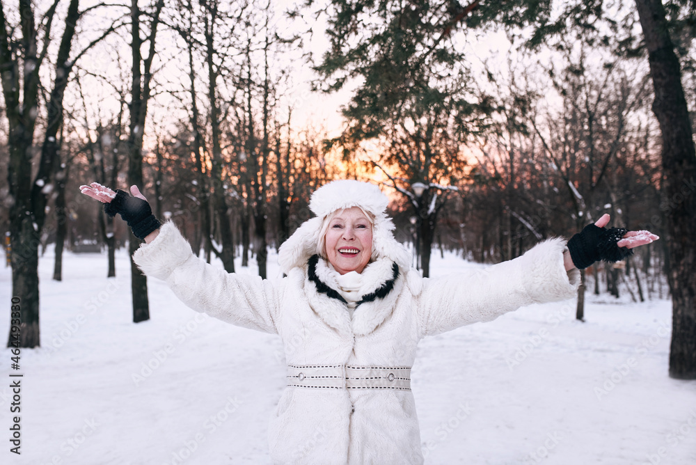 Fototapeta premium senior woman in white hat and fur coat enjoying winter in snow forest. Winter, age, season concept
