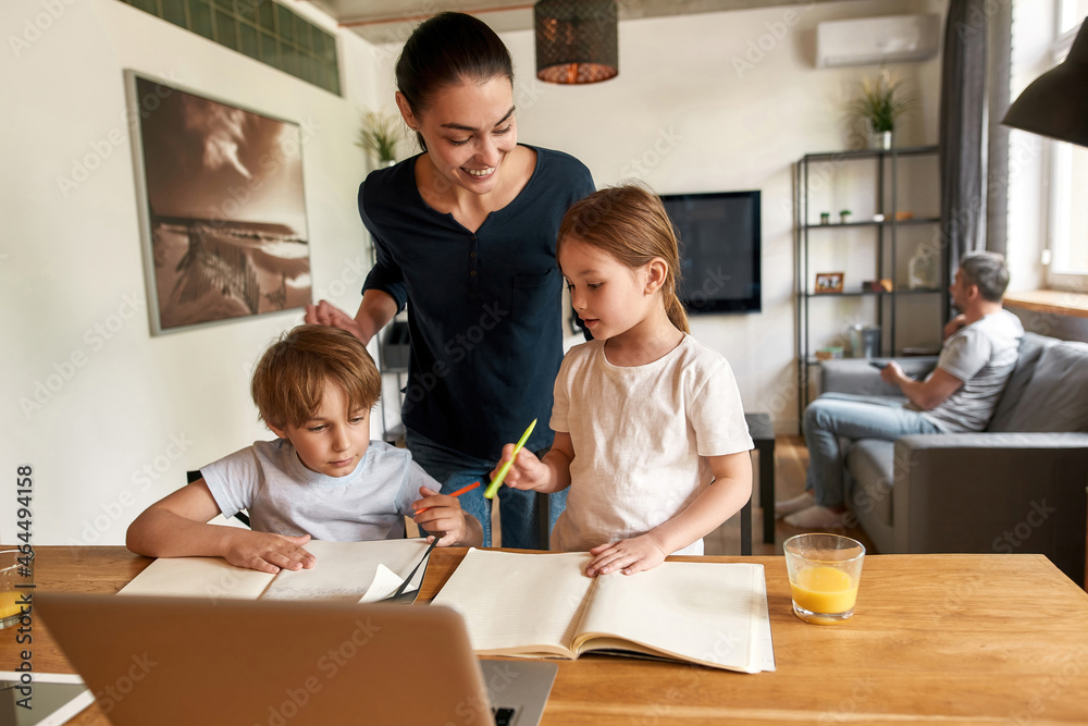 Smiling mom control kids doing homework for school