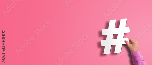 hand holding hash symbol, hashtag against pink background, social media concept with copy space photo