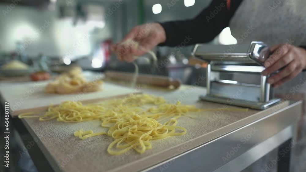Woman hands preparing fresh fettucine pasta using traditional machine