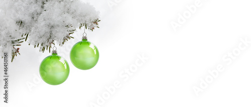 Zwei grüne Weihanchtslugeln an einem schneebedecktem Tannenzweig