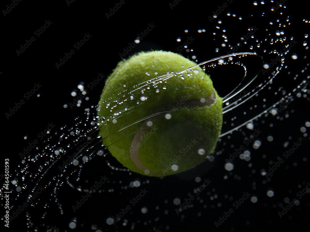 Yellow tennis ball with water splashes on a black background
