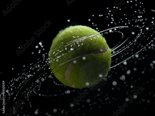 Yellow tennis ball with water splashes on a black background © Иван Григорьев