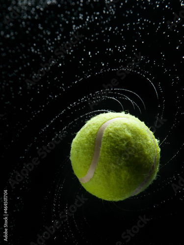 Yellow tennis ball with water splashes on a black background © Иван Григорьев
