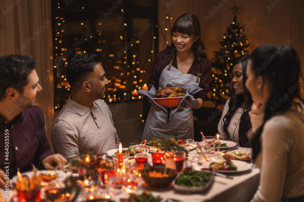 holidays and celebration concept - multiethnic group of happy friends having christmas dinner at home
