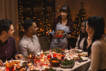 holidays and celebration concept - multiethnic group of happy friends having christmas dinner at home
