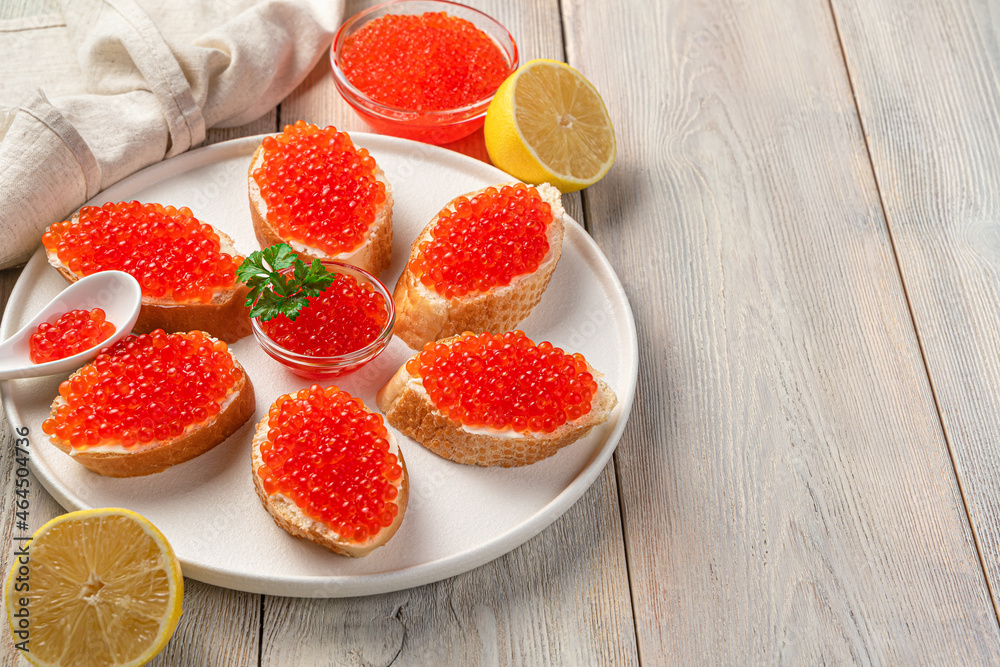 Sandwiches with red caviar and lemon on a beige background. Side view, copy space.