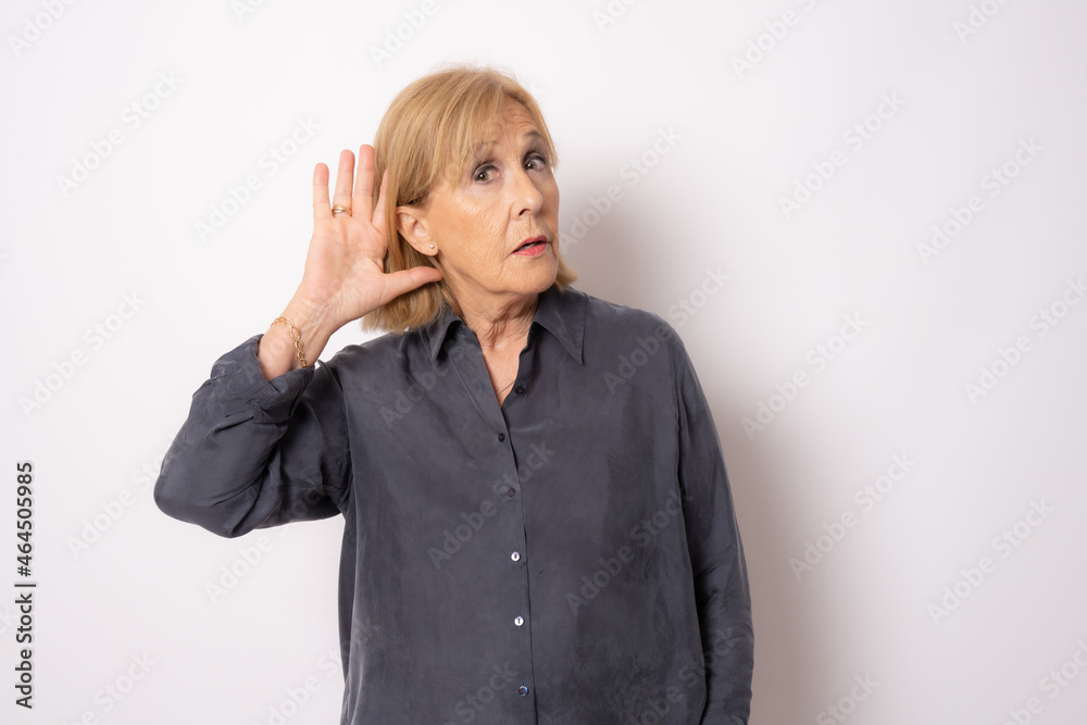 Portrait of cheerful old woman in blue shirt making listening gesture, isolated on white background Portrait of cheerful old woman in blue shirt making listening gesture, isolated on white background