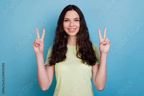 Photo of cheerful positive girl show v-sign shiny white smile posing on blue background