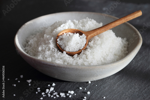 Flower of salt from Guerande - France in a ceramic grey bowl with wooden spoon on a black slate background. Traditional  french natural sea salt of high quality close up.