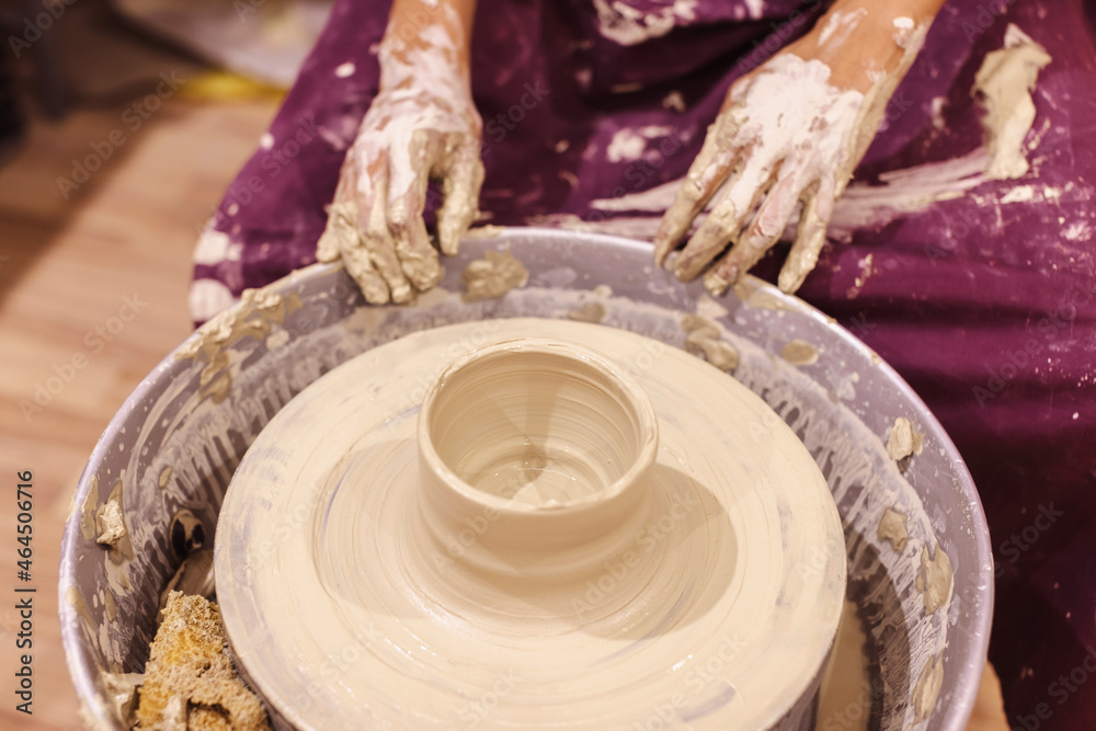 Pottery workshop. Female ceramic artist molding clay on pottery wheel. Creative handmade craft.