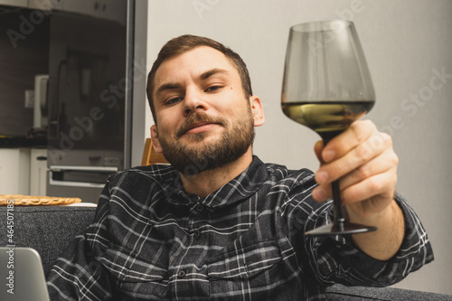 The handsome adult man smiles and holds the wine glass in his hand.
