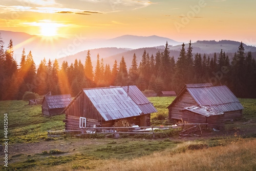small wooden house in the mountains. incredible sunset over the top of the mountains. rays of the sun.
