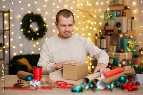 Young happy man wrapping christmas gifts at home