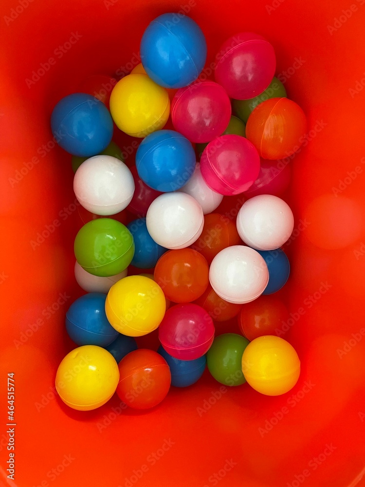Top view shot of many colorful plastic balls in red container in childrens room Top view shot of many colorful plastic balls in red container in childrens room
