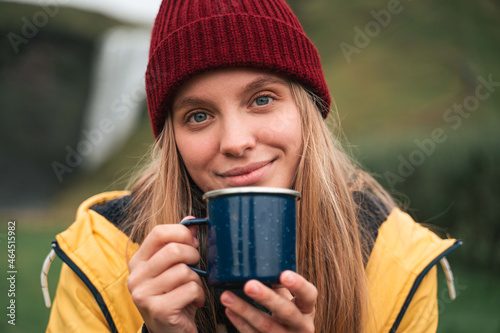 Woman holding blue mug and smiling to the camera while warming up © Yakobchuk Olena