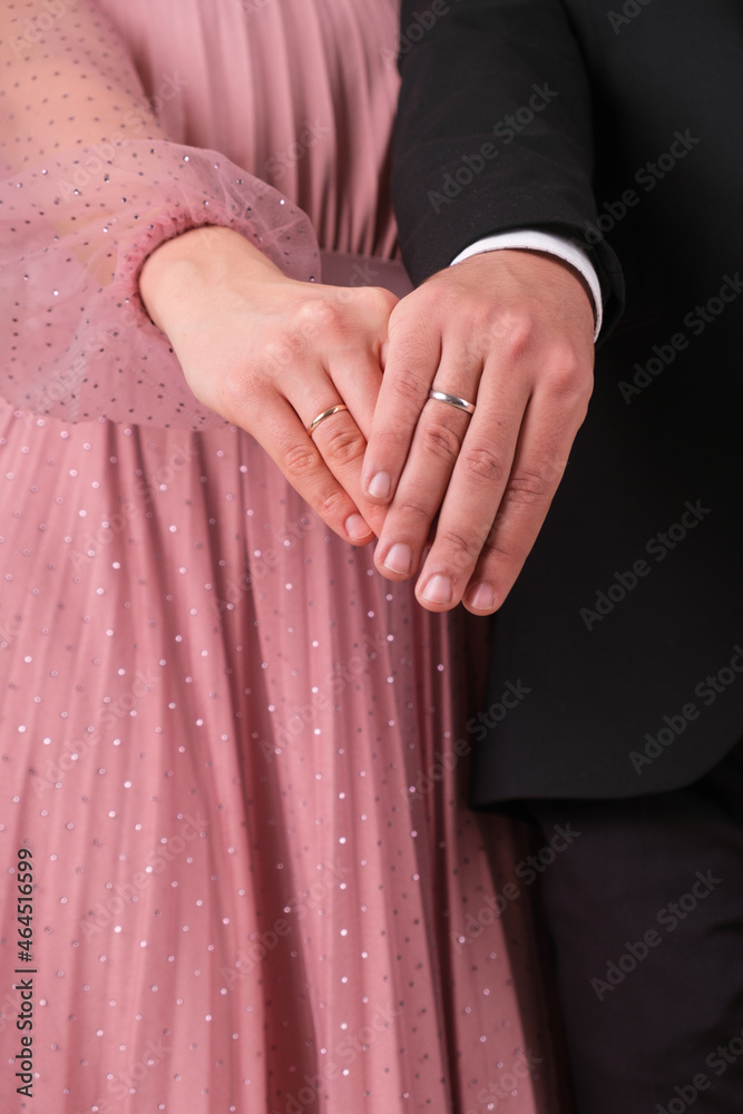 Hands of the bride and groom with wedding rings of white and yellow gold close-up
