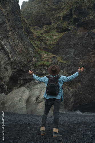 Man wearing hat and backpack raised hands and admiring of the wild nature