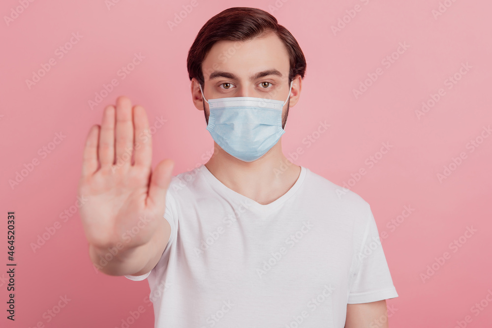 Portrait of confident protester guy wear medical mask raise hand show stop gesture on pink background Portrait of confident protester guy wear medical mask raise hand show stop gesture on pink background