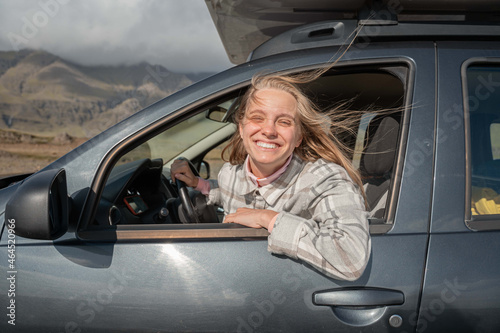 Woman with smile sitting at the driver place at her car and riding to meet new adventures