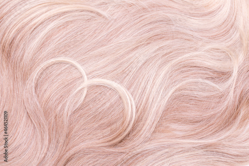 Background hair closeup. Female long blond hair close-up as a background. Beautifully laid wavy shiny curls. Hair coloring. Hairdressing procedures. Copy space with space for text.