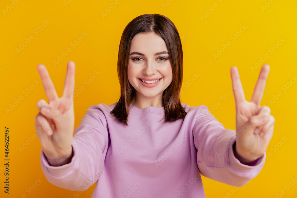 Photo of young lovely girl show fingers peace cool v-symbol wear jumper isolated over yellow color background