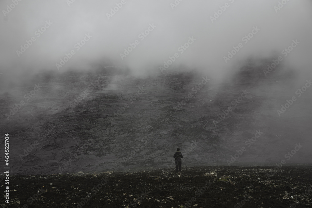 Fototapeta premium Lonely person standing at the black rocks and looking at the distance
