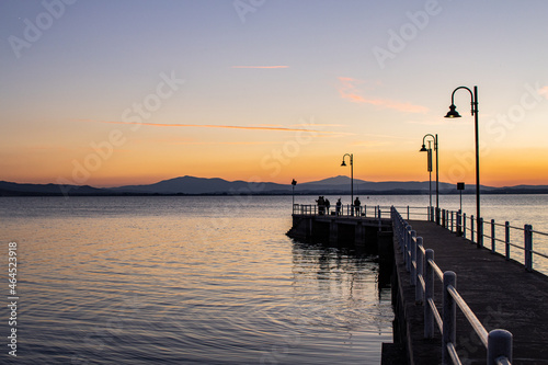 Lake with jetty at sunset. Relaxing Italian landscape at sunset in autumn. Trasimeno lake at sunset