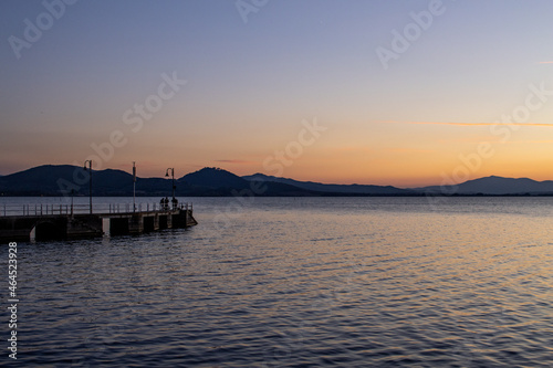 Lake with jetty at sunset. Relaxing Italian landscape at sunset in autumn. Trasimeno lake at sunset