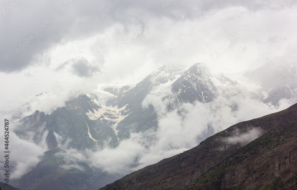 Beautiful Himalayan landscape of isty clouds around snow capped mountains in the town of Keylong in the Lahaul district in Himachal Pradesh, India.