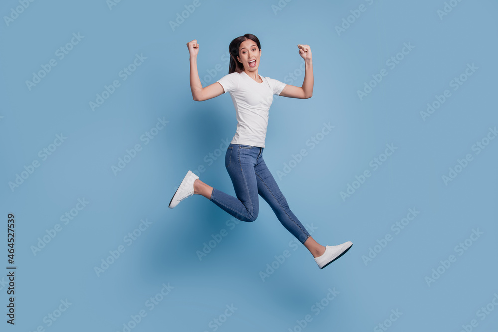 Portrait of energetic carefree excited lady jump run winner concept on blue background
