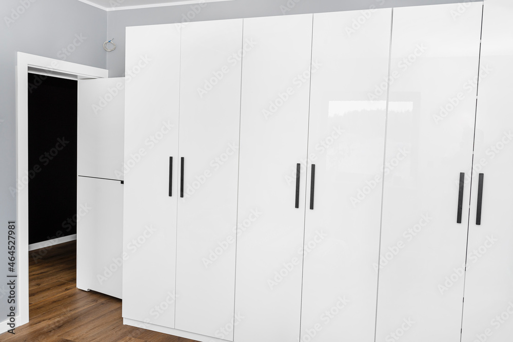 Large and high wardrobe in the bedroom with white fronts and black handles. Large and high wardrobe in the bedroom with white fronts and black handles.