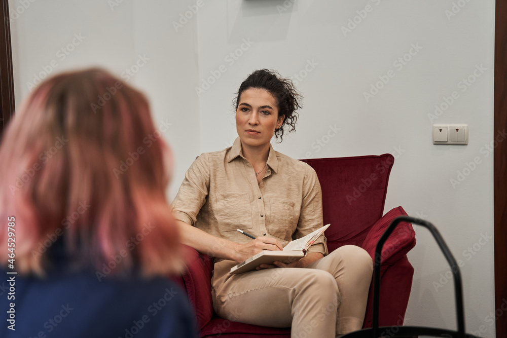 Female friendly psychologist talking with patients on therapy session - obrazy, fototapety, plakaty 